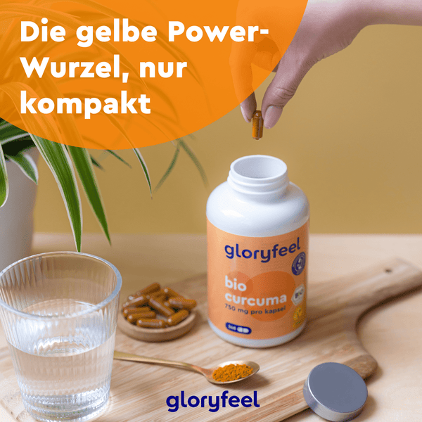 Eine Hand greift nach einer Bio Curcuma Kapsel aus einer offenen Flasche der gloryfeel GmbH, die neben einem Glas und einem Löffel auf einem Tisch steht. Deutscher Text auf orangefarbenem Kreis und Etikett.