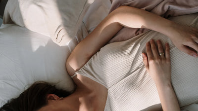 Frau im Bett hält sich den Bauch