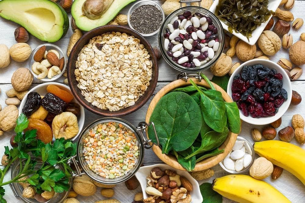 gesunde Lebensmittel wie Avocados, Nüsse, Haferflocken, Bohnen und Spinat.