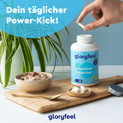 Eine Hand hält Pillen über einer Flasche Magnesiumbisglycinat-Kapseln der gloryfeel GmbH auf einem Tisch mit einer Pflanze, einer Müslischale und einem Löffel, begleitet vom deutschen Text „Dein täglicher Power-Kick!“.