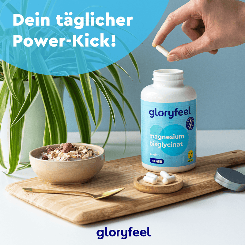 Eine Hand hält Pillen über einer Flasche Magnesiumbisglycinat-Kapseln der gloryfeel GmbH auf einem Tisch mit einer Pflanze, einer Müslischale und einem Löffel, begleitet vom deutschen Text „Dein täglicher Power-Kick!“.