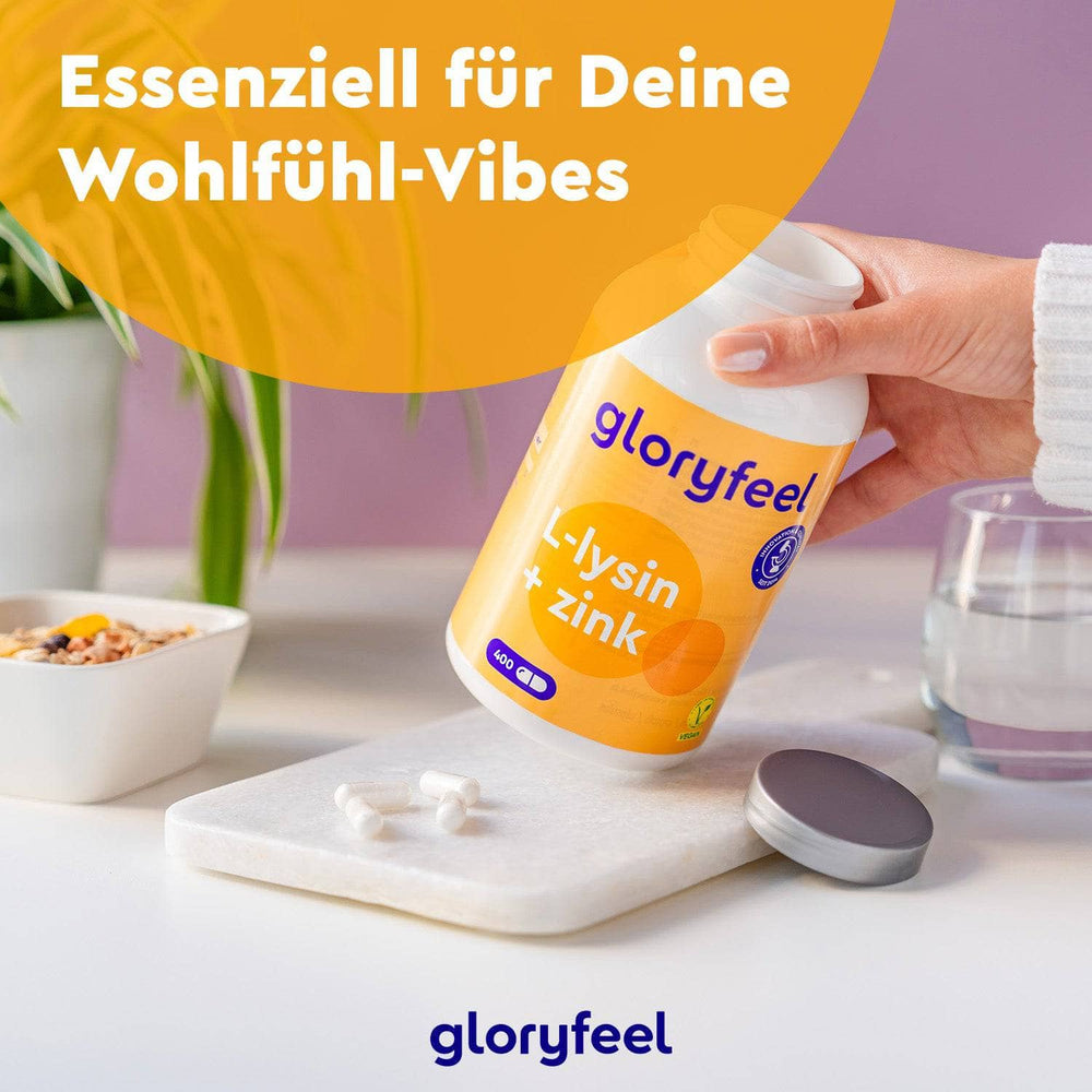 Eine Person schüttet Kapseln aus einer L-Lysin + Zink Kapseln-Flasche der Gloryfeel GmbH auf ein Tablett, im Hintergrund eine Pflanze und eine Schüssel. Der Text lautet „Essenziell für Deine Wohlfühl-Vibes.