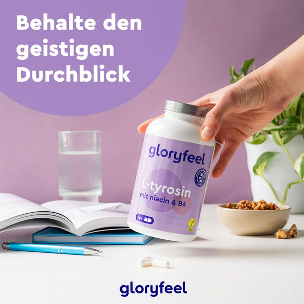 Eine Hand hält eine Flasche L-Tyrosin Kapseln der gloryfeel GmbH neben einem Glas Wasser, einem Stift, einem aufgeschlagenen Notizbuch und einer Schale mit Nüssen auf einem Schreibtisch. Darüber wird ein deutscher Text angezeigt.