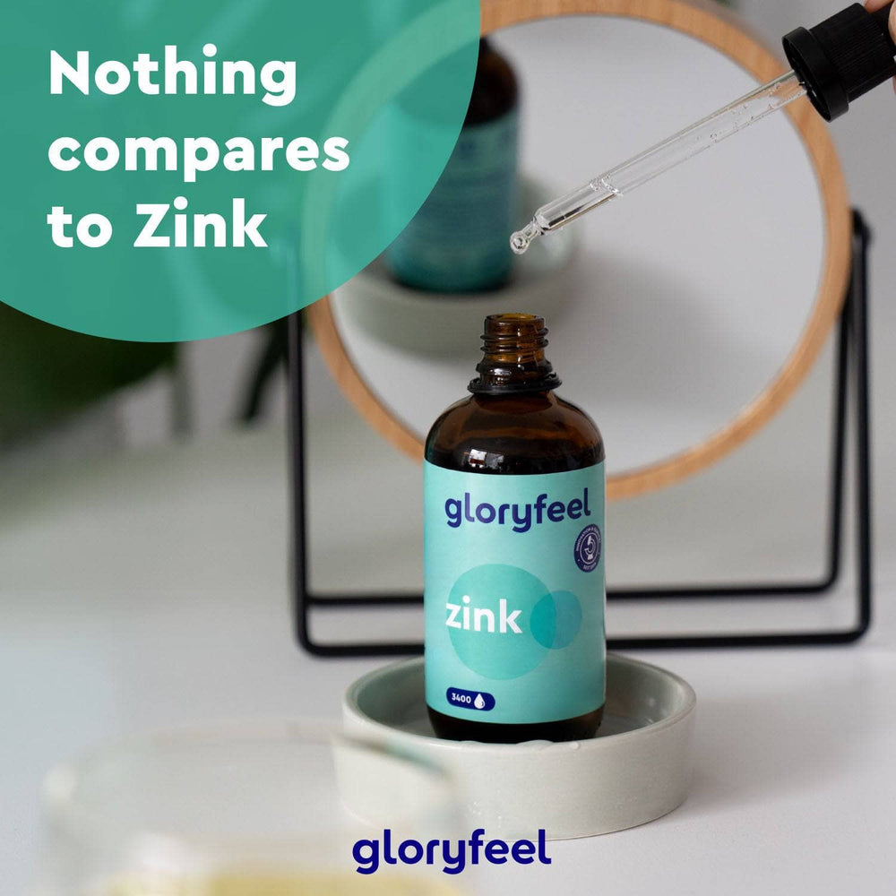 Eine Pipette schwebt über einer Flasche mit der Aufschrift „Zink Tropfen“ der gloryfeel GmbH, im Hintergrund ein runder Spiegel. Der Text lautet: „Nichts ist mit der Bioverfügbarkeit von Zink vergleichbar.“.