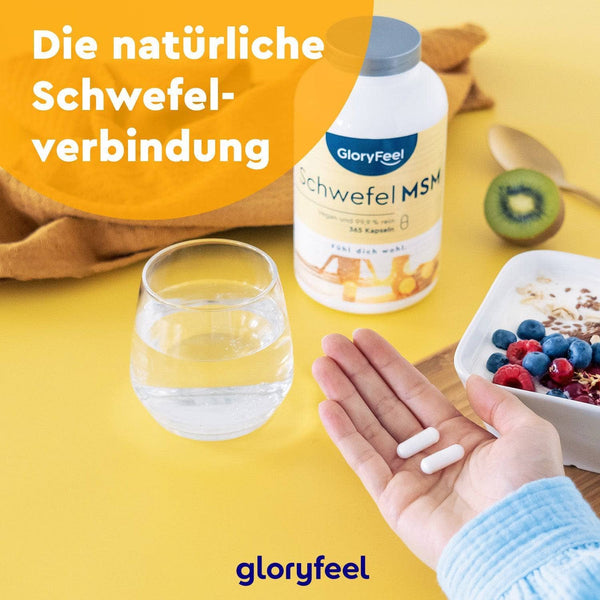 A hand holds two white capsules near a table featuring a Tri-Magnesium Dicitrat + MSM supplement bottle, a glass of water, and a bowl of berries, with German text evident on the bottle and image.