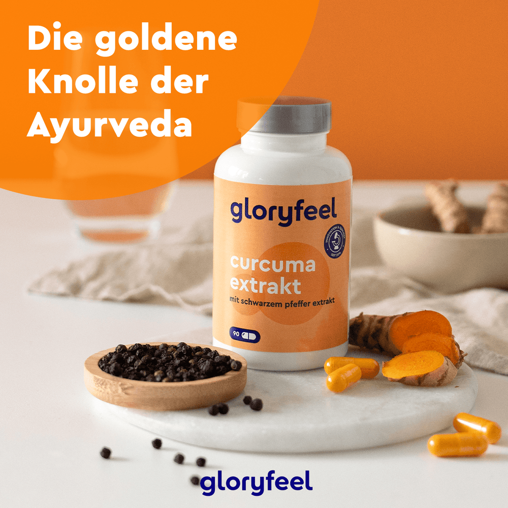 Auf einem Tisch steht eine Flasche „Gloryfeel Gutes Bauchgefühl Set“, begleitet von frischen Kurkumawurzeln und schwarzen Pfefferkörnern.