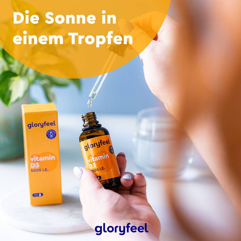 Eine Person entnimmt mit einer Pipette Flüssigkeit aus einer Flasche mit Vitamin D3 Tropfen 5000 I.E. der gloryfeel GmbH. Der umgebende deutsche Text und die Marke gloryfeel sind sichtbar.