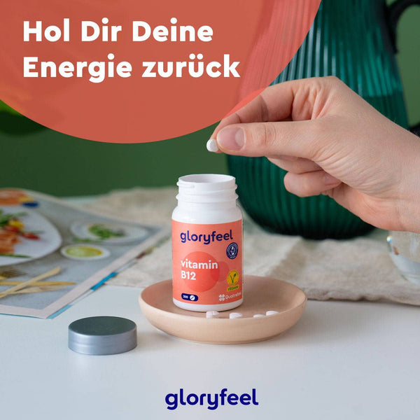 Eine Hand hält eine Tablette über einer offenen Flasche Vitamin B12 Tabletten der Gloryfeel GmbH auf einem Teller, darüber steht der Text „Hol Dir Deine Energie zurück“.