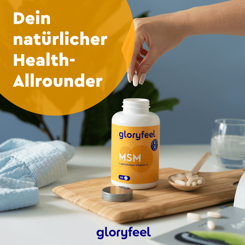 Eine Hand greift nach einer Kapsel neben einer offenen Flasche „gloryfeel“ MSM + Vitamin C Tabletten auf einem Tisch mit weiteren Kapseln und einem Glas Wasser. Auf dem Tisch steht „Dein Gesundheits-Allrounder“. Diese kraftvolle organische Schwefelverbindung der gloryfeel GmbH unterstützt Sie auf Ihrem Weg zu mehr Gesundheit.