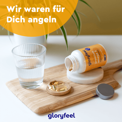 Omega-3 TG Form Kapseln der gloryfeel GmbH auf einem Holztablett mit einem Glas Wasser verteilen, unter dem Text „Wir waren für Dich angeln“. Diese Kapseln, reich an EPA und DHA, steigern Ihr Wohlbefinden. Das Logo am Boden zeigt „gloryfeel“.