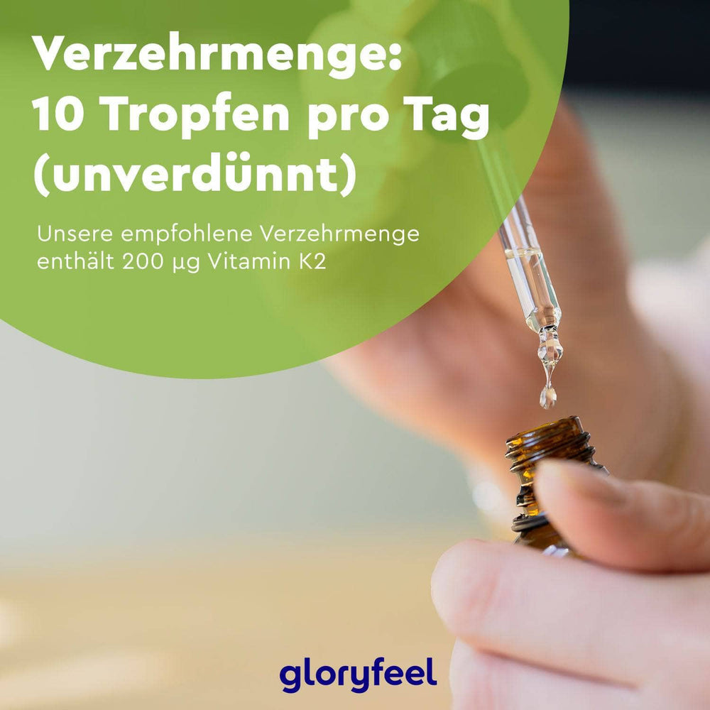 Eine Hand hält eine Pipette über einer kleinen Flasche. Der deutsche Text empfiehlt täglich 10 unverdünnte Tropfen Vitamin K2 für eine Dosierung von 200 µg. Angereichert mit MCT-Öl für optimale Aufnahme, trägt das Logo unten die Aufschrift „gloryfeel GmbH“.