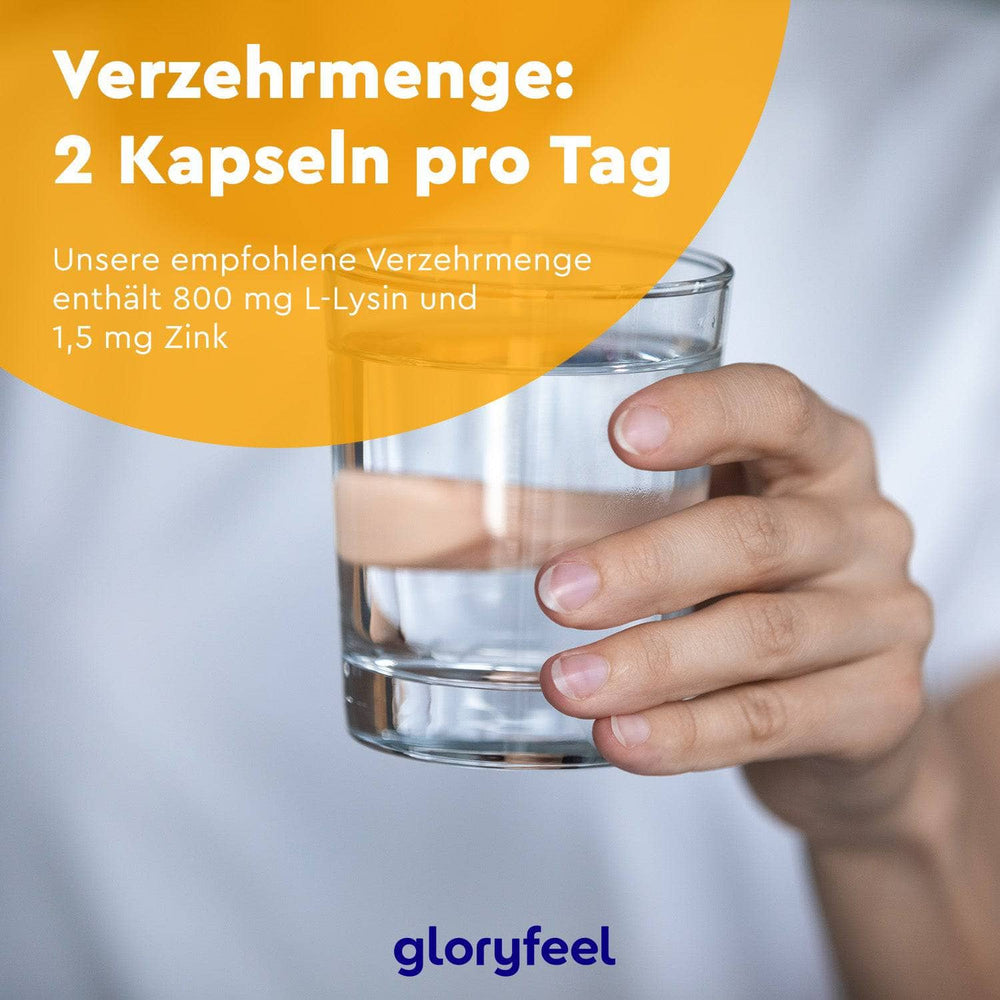 Eine Hand hält ein Glas Wasser. Darauf steht der deutsche Text zum Nahrungsergänzungsmittel „L-Lysin + Zink Kapseln“ der gloryfeel GmbH: „Dosierung: 2 Kapseln täglich, enthalten 800 mg L-Lysin und 1,5 mg Zink.“ Unten das Markenlogo.