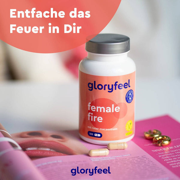 Eine Flasche „Rotes Maca Kapseln“ der gloryfeel GmbH steht auf einem Tisch neben einer aufgeschlagenen Zeitschrift und einigen Kapseln. Darüber steht auf Deutsch „Entfache das Feuer in Dir.“.
