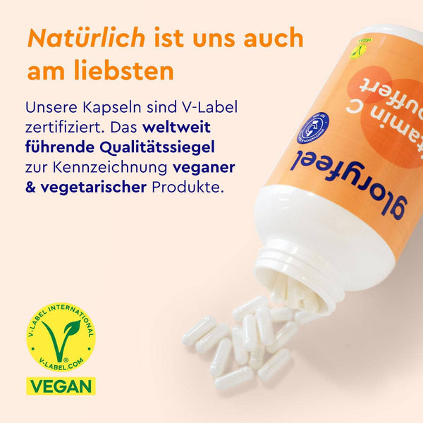 Eine weiße Flasche mit der Aufschrift „gloryfeel GmbH Vitamin C Kapseln gepuffert“ verteilt weiße Kapseln auf einer hellen Oberfläche. Der Text hebt die veganen und vegetarischen Eigenschaften des V-Labels hervor, unten links befindet sich ein grünes V-Label-Logo.